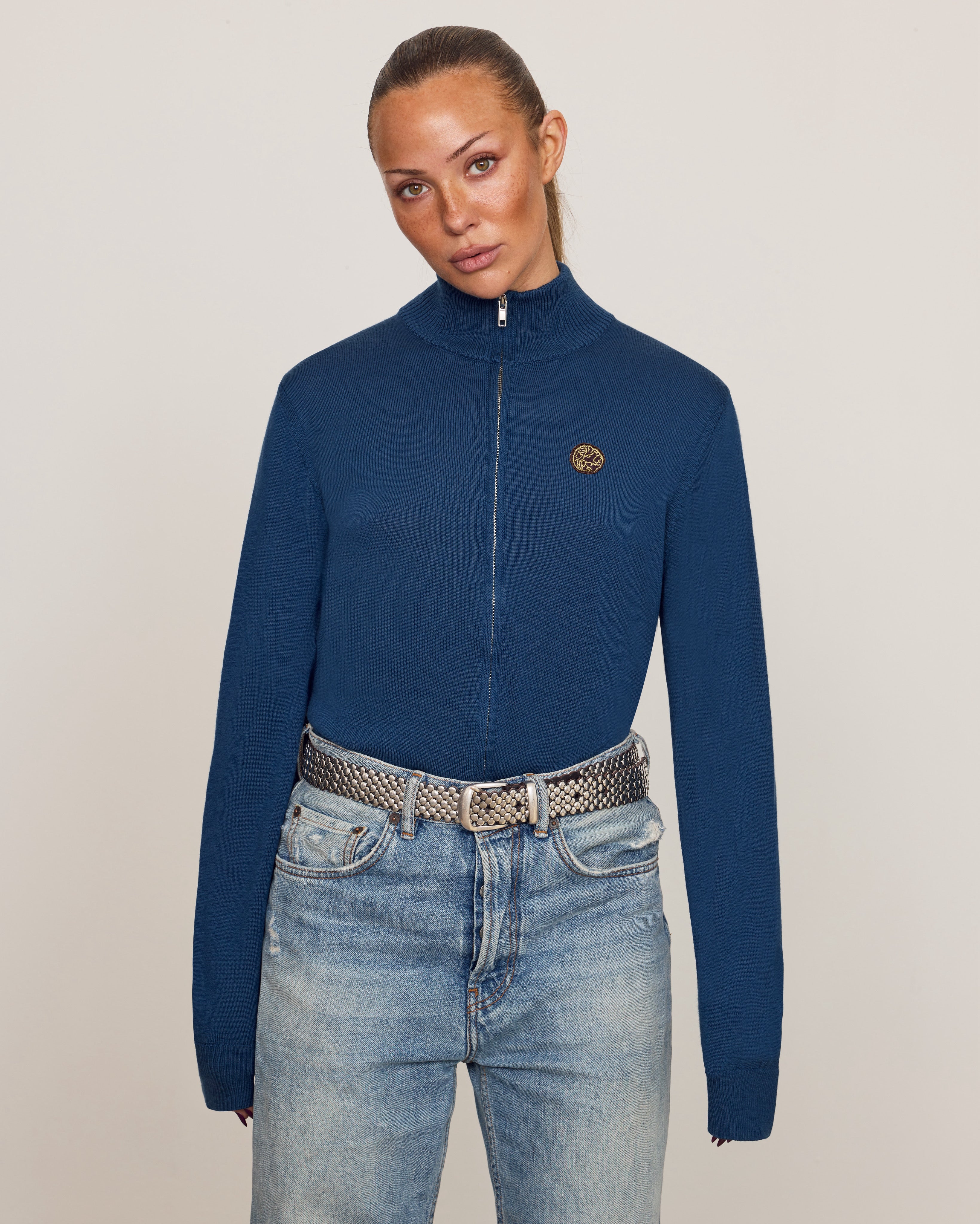 Savoj unisex full-zip merino wool cardigan, close-up gold emblem embroidery.
